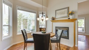 A dining room with a round table, four chairs, a chandelier, a fireplace, and large windows. - Portland Area Retreat in North Wine Country! (Tualatin)