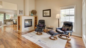 A spacious living room with hardwood flooring, two leather armchairs, a fireplace, and a large window with blinds. - Portland Area Retreat in North Wine Country! (Tualatin)