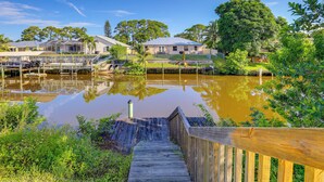A wooden staircase leading to a dock over a calm water body, surrounded by lush greenery and residential buildings. - Charming St Lucie River Retreat w/ Pool & Dock! (Port Saint Lucie)