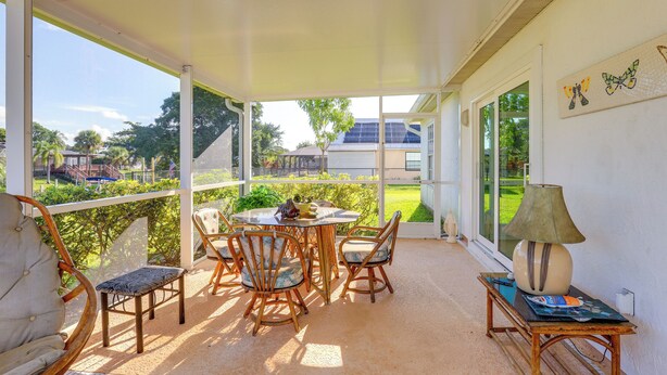 A covered patio with a table and chairs, a lamp, and a view of the surrounding area. - Charming St Lucie River Retreat w/ Pool & Dock! (Port Saint Lucie)