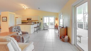 A spacious living area with a sofa, a dining table, and a kitchen in the background. - Charming St Lucie River Retreat w/ Pool & Dock! (Port Saint Lucie)