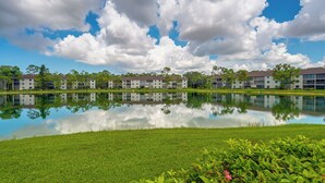 A modern building complex with a reflective pond in front, surrounded by greenery and trees. - 3 Mi to Beaches: Naples Condo w/ Pool Access! (Naples)