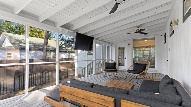 A covered porch with a wooden bench and two chairs, a ceiling fan, and a TV mounted on the wall. - 2 Mi to Downtown Austin: Family Home w/ Porch! (Austin)