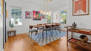 A dining area with a wooden table and chairs, a checkered rug, and artwork on the walls. - 2 Mi to Downtown Austin: Family Home w/ Porch! (Austin)