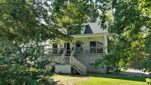 A two-story house with a porch, a staircase, and a stone wall. - Waterfront Home Near Wilson Lake w/ Covered Porch! (Killen)
