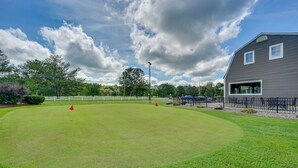 Ein Golfplatz mit Clubhaus, einem eingezäunten Bereich und blauem Himmel.