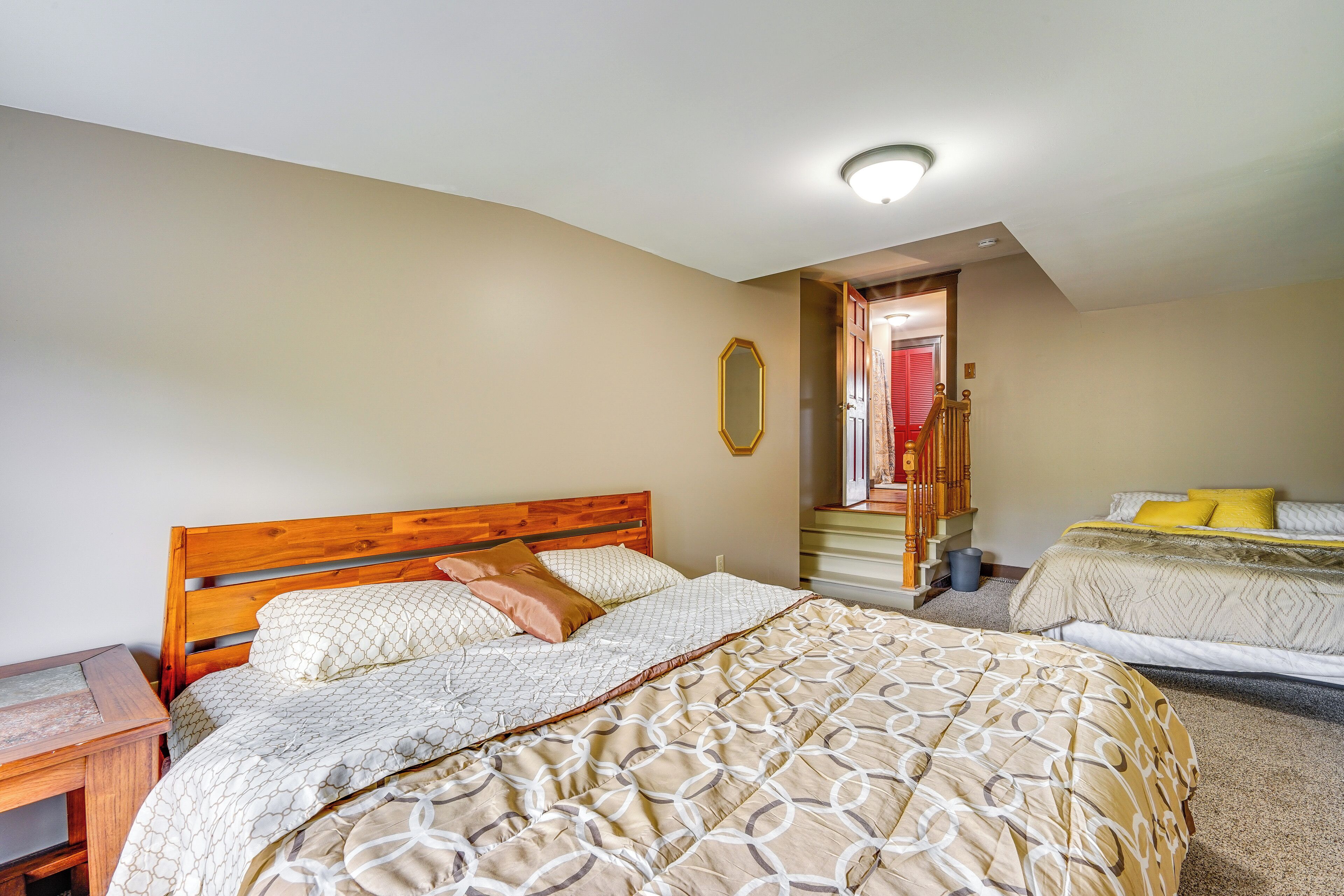 A bedroom with two beds, a wooden headboard, a bedside table, and a mirror on the wall.