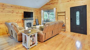 A cozy cabin interior with a fireplace, leather sofa, and a television. - Mtn View + Fire Pit: Pet-friendly Woodlawn Cabin! (Woodlawn)