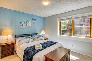 Un dormitorio con cama, mesitas de noche, una ventana y decoración en la pared.