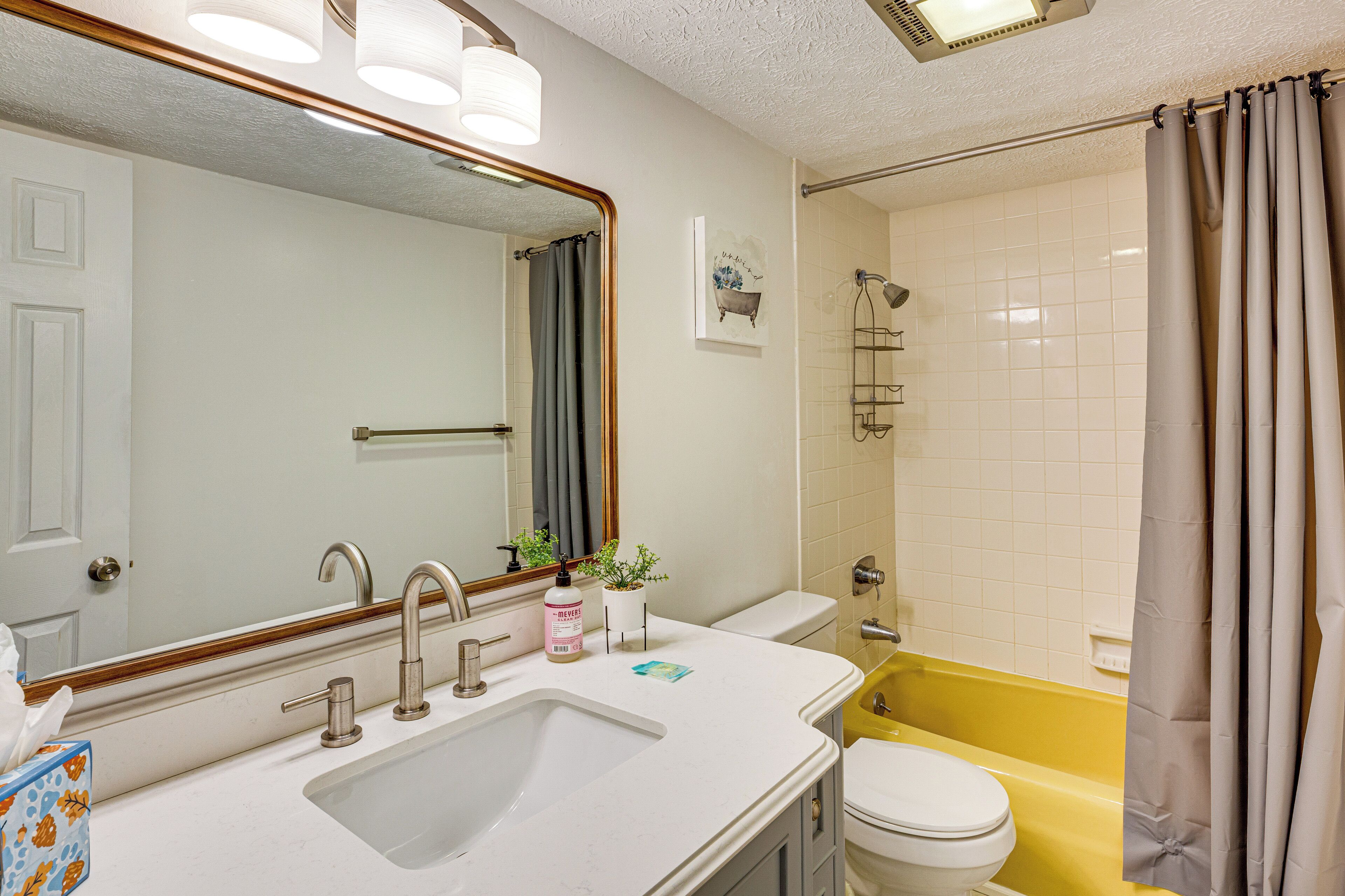 A bathroom with a white sink, a mirror, a toilet, and a bathtub.
