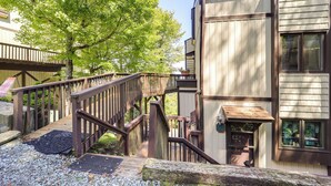 A wooden staircase leading to a building with a balcony, surrounded by trees. - Hike, Ski & Fish! Sunset-view Condo in Beech Mtn (Banner Elk)