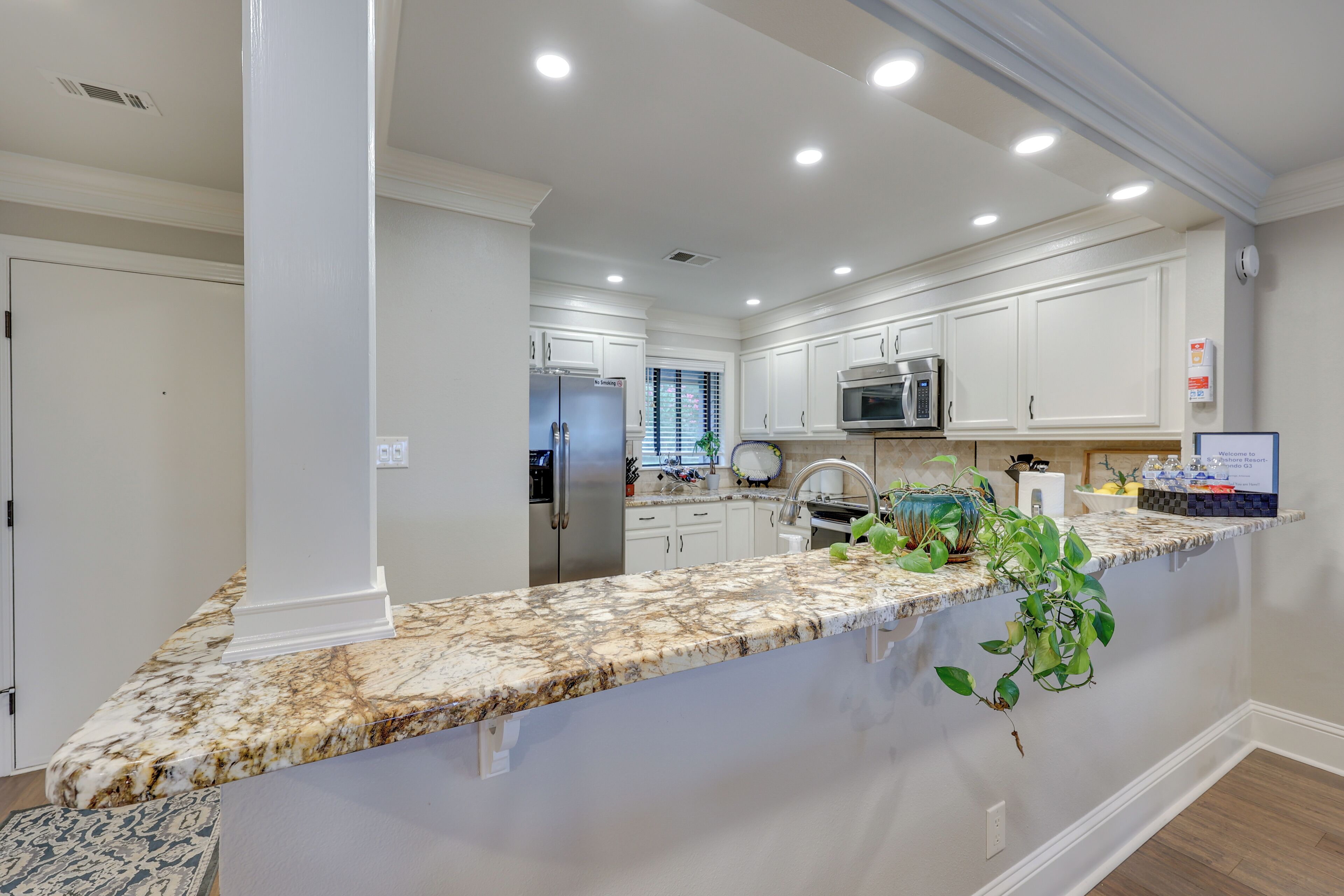 A modern kitchen with white cabinetry, granite countertops, stainless steel appliances, and a built-in microwave.