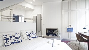 Ein Schlafzimmer mit einem großen Bett, einem Kamin, einem Schreibtisch mit Stuhl und einem Kleiderschrank.
