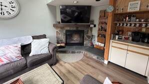 Una sala de estar con chimenea, televisor, sofá y espacio para café.