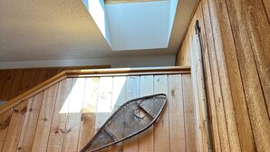 Un interior de madera con tragaluces, un ventilador de techo y un pasillo que conduce a una puerta.