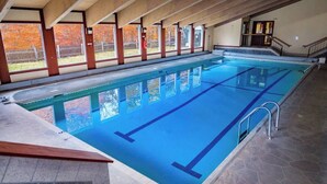 Una piscina interior con agua azul cristalina, paredes de azulejos y suelo de piedra.