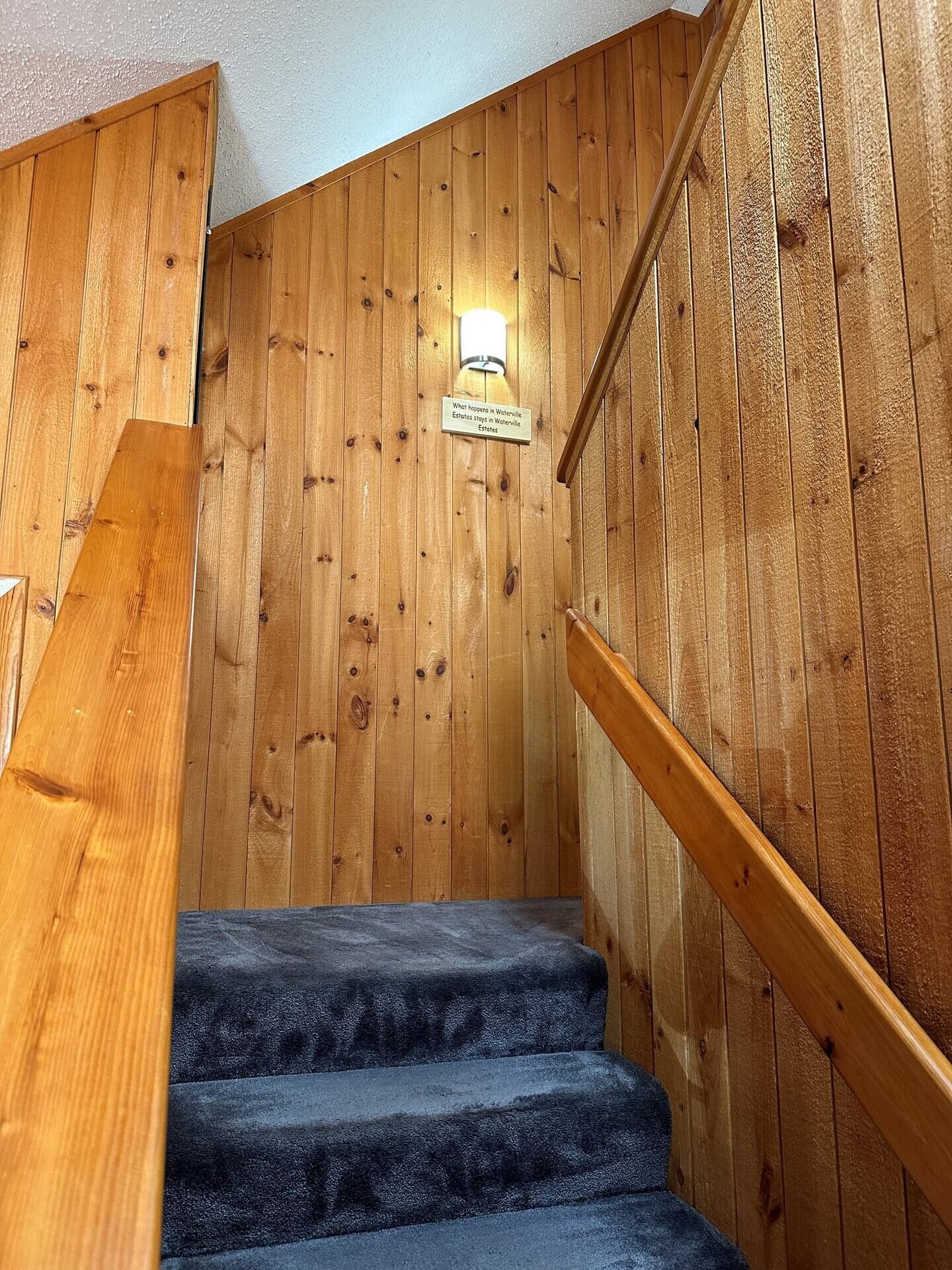 Eine Holztreppe mit Handlauf und einem Schild darüber.