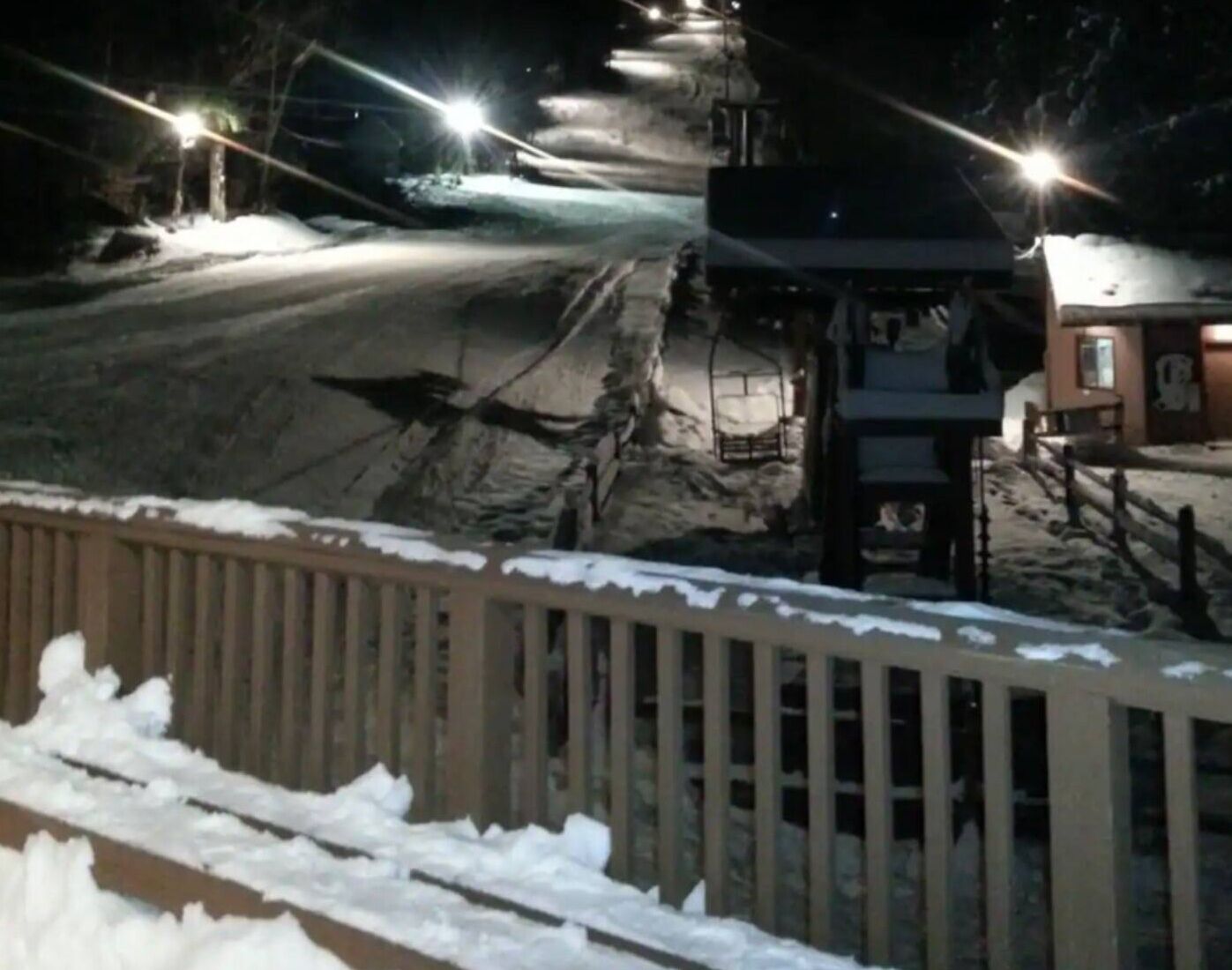 Una strada innevata di notte illuminata da lampioni.