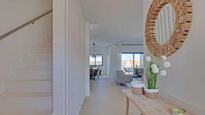 Un intérieur moderne avec un escalier, un coin repas et un grand miroir au mur.