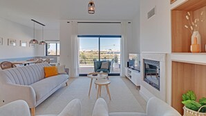 Un salon moderne avec un canapé, des fauteuils, une petite table et une cheminée.