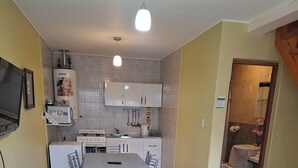 Ein kompakter Wohnbereich mit Essplatz, Küchenzeile und kleinem Badezimmer.