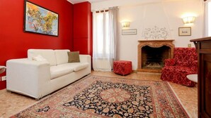 A living room with a white sofa, red patterned armchair, and a red wall. - In the Art Quartier (Venezia)