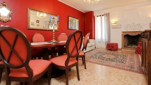 A dining room with a red wall, a chandelier, a fireplace, and a patterned rug. - In the Art Quartier (Venezia)