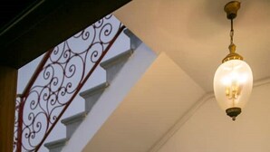 A staircase with ornate metal railings and a hanging light fixture. - In the Art Quartier (Venezia)