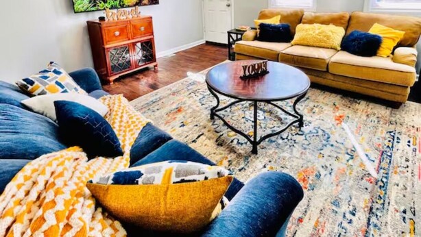 A living room with a sofa, coffee table, and a television on the wall.