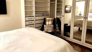 A bedroom with a bed, a wardrobe with multiple drawers, a mirror, and a nightstand with a lamp. - Charming Hydrangea Cottage in Sewickley Village 4bd/1.5 b - 20 min to Pittsburgh (Sewickley)