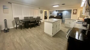 Een moderne keuken met een centraal eiland, een eethoek met stoelen en een plafondventilator.