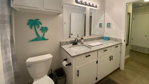 Een badkamer met toilet, wastafel, een wastafelmeubel en een spiegel.