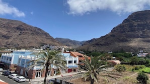 Un pueblo costero con edificios, una carretera y montañas al fondo.