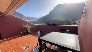 Una terraza con una mesa y sillas, una planta en maceta y vistas a montañas.