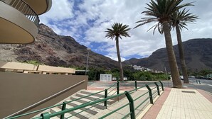 Un escalier menant à un bâtiment, avec une montagne en arrière-plan, des palmiers et un ciel dégagé.