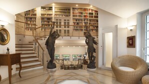 Un amplio salón con techo alto, una escalera que lleva a una biblioteca y un espacio de descanso acogedor.