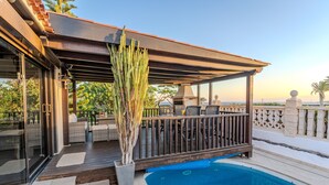 A covered outdoor area with a pool, seating, and a cactus plant.
