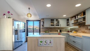 A modern kitchen with light blue cabinets, a central island, and a view of the city.
