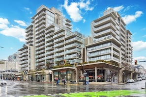 A modern high-rise building with multiple balconies and a ground-level commercial area. - Waterfalls Hotel - Kings Corner - Resort Living (Victoria)