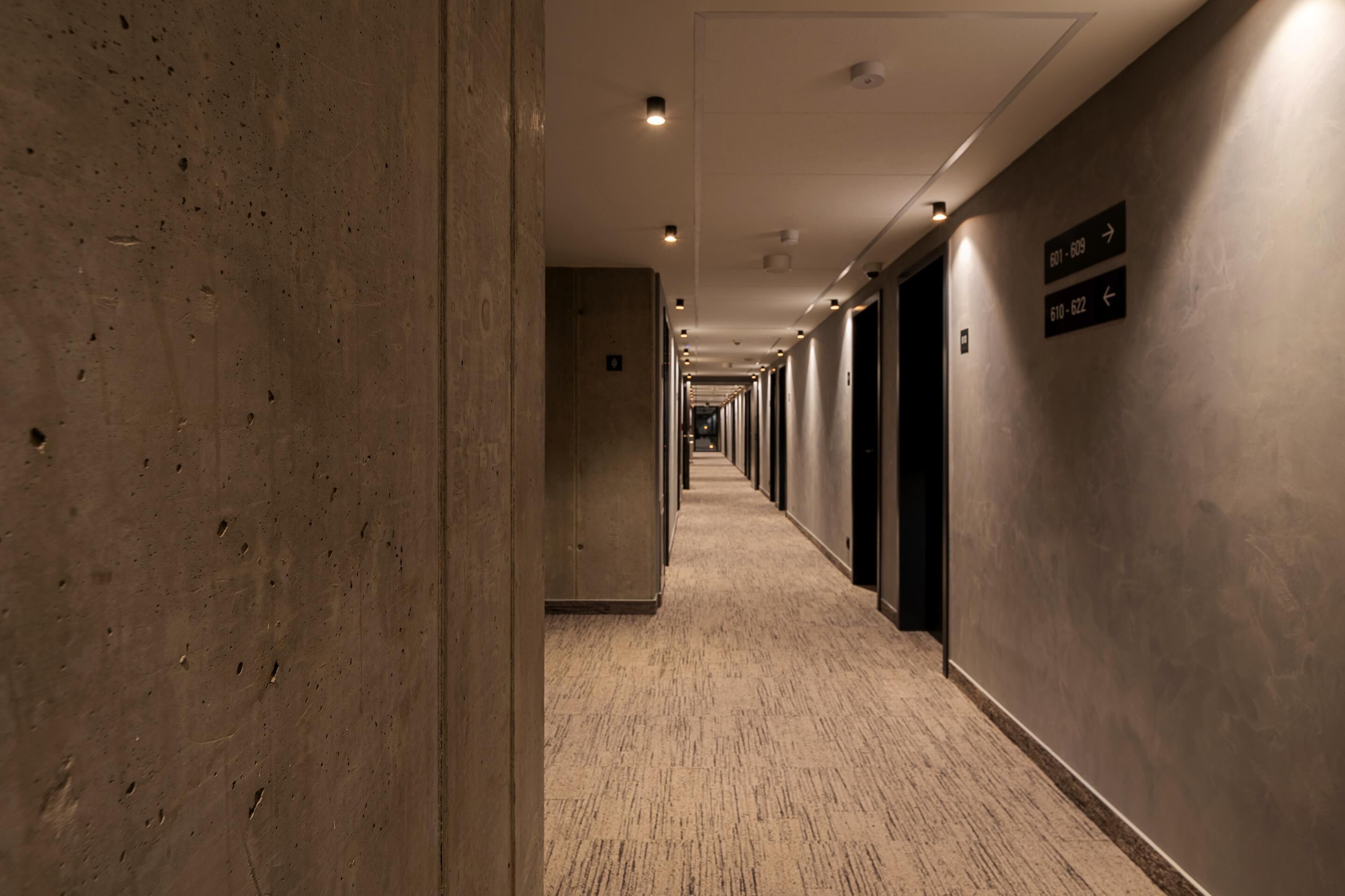 Un long couloir étroit, avec des portes des deux côtés, menant à des pièces individuelles.