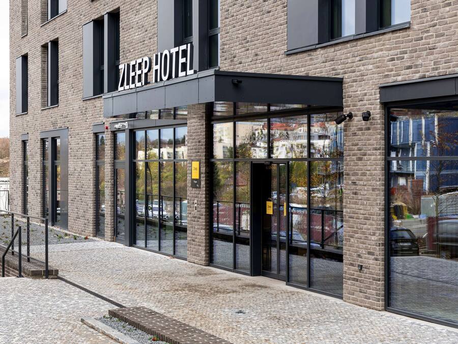 Un hotel con fachada de ladrillo moderno, amplias ventanas y una entrada visible.