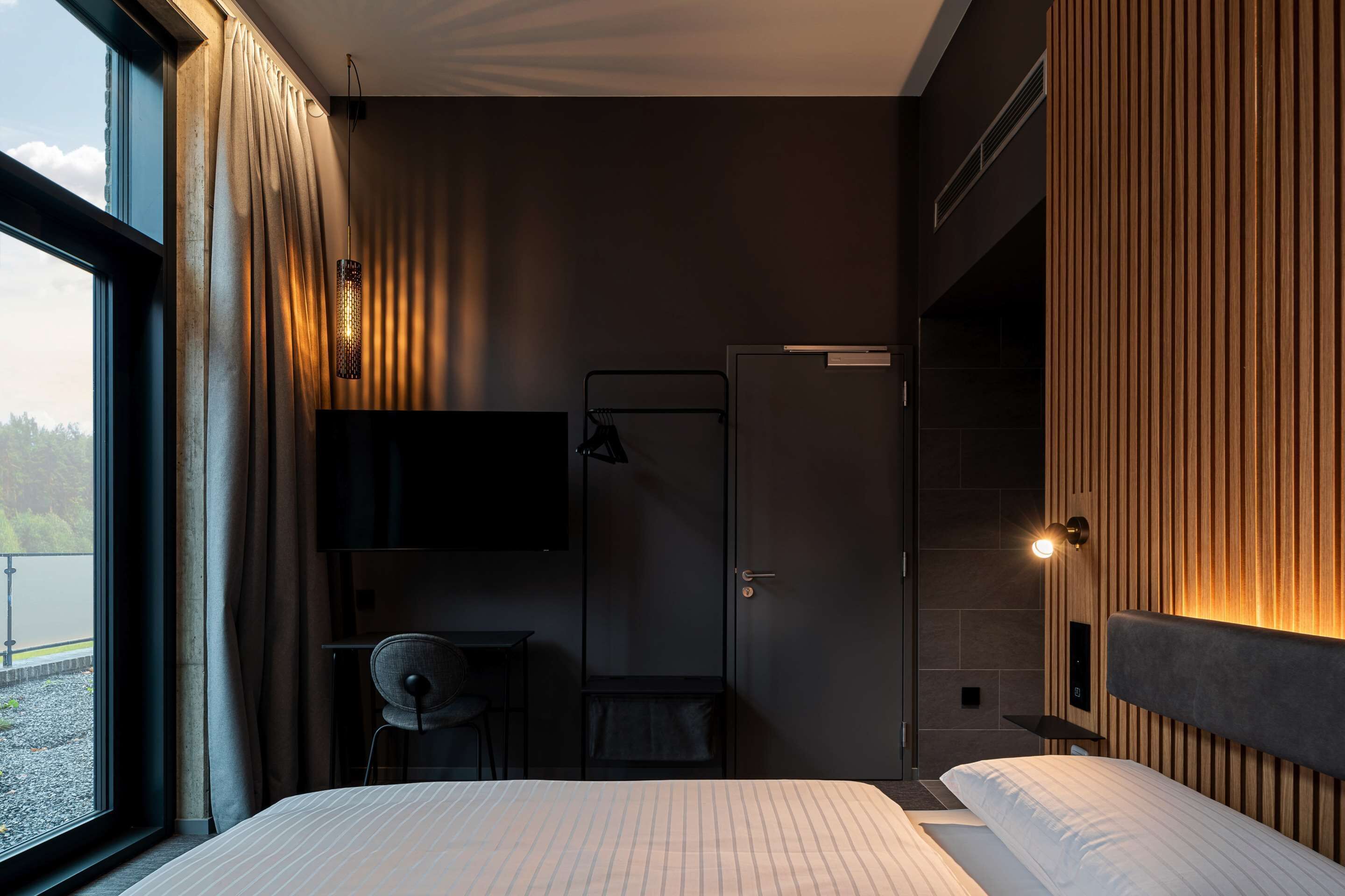 Una habitación de hotel moderna con una cama grande, un escritorio, una silla y un televisor.