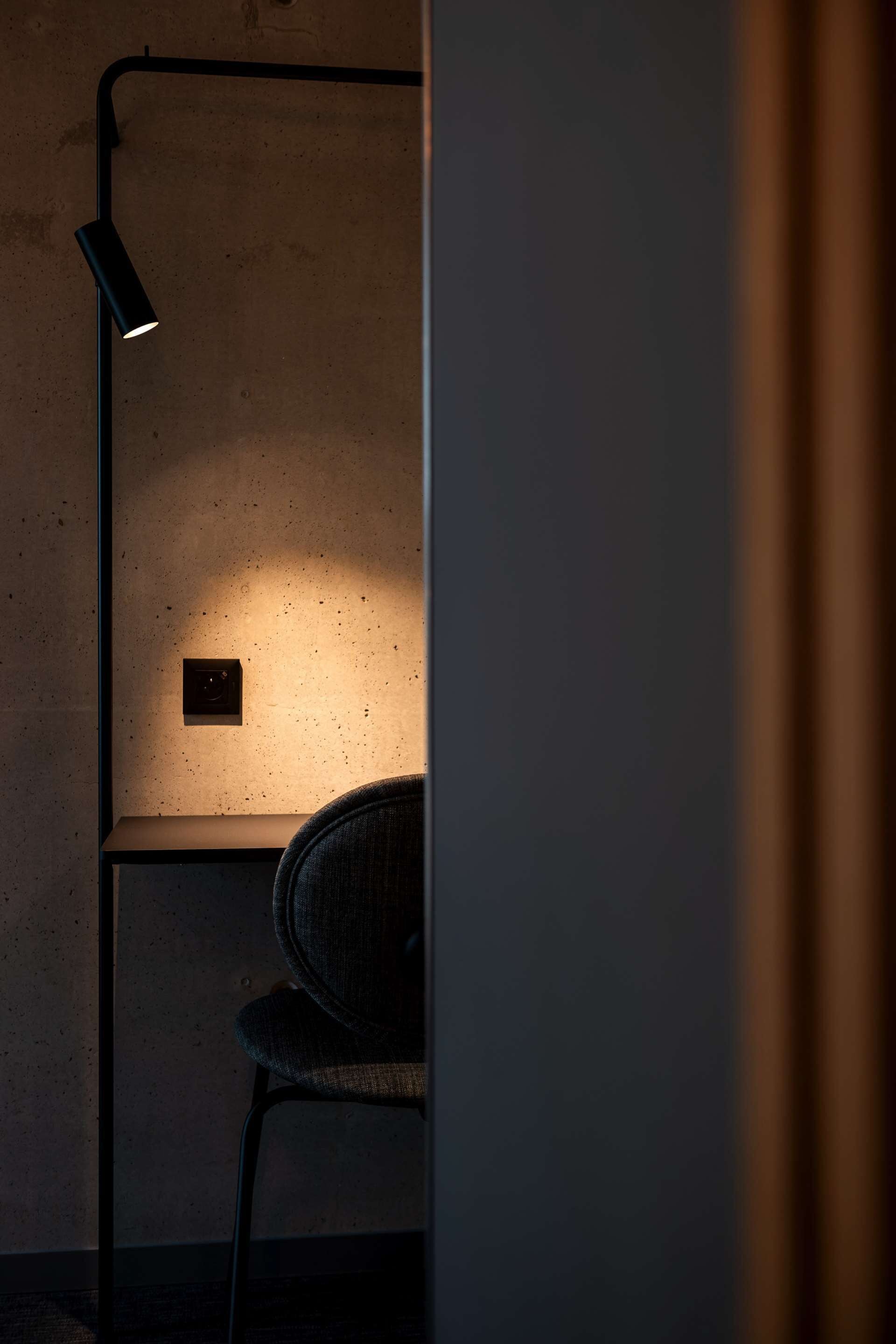 Een kamer met weinig licht, een stoel en een wandlamp.