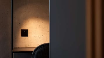 Una habitación con poca luz, una silla y una lámpara fijada a la pared.