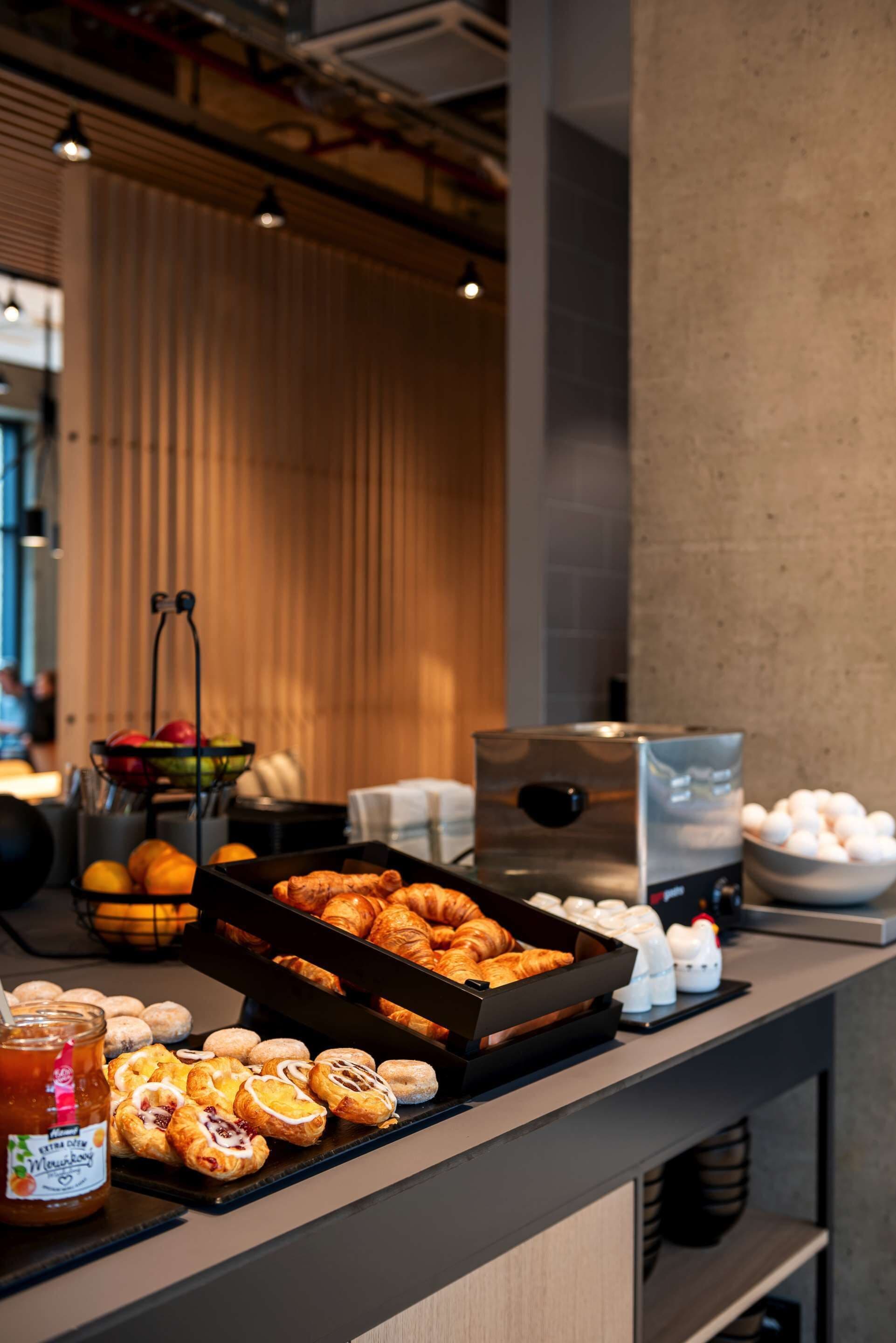 Een ontbijtbuffet met gebak, fruit en toevoegingen.
