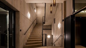 Een modern interieur met een betonnen trap, metalen leuningen en hanglampen.