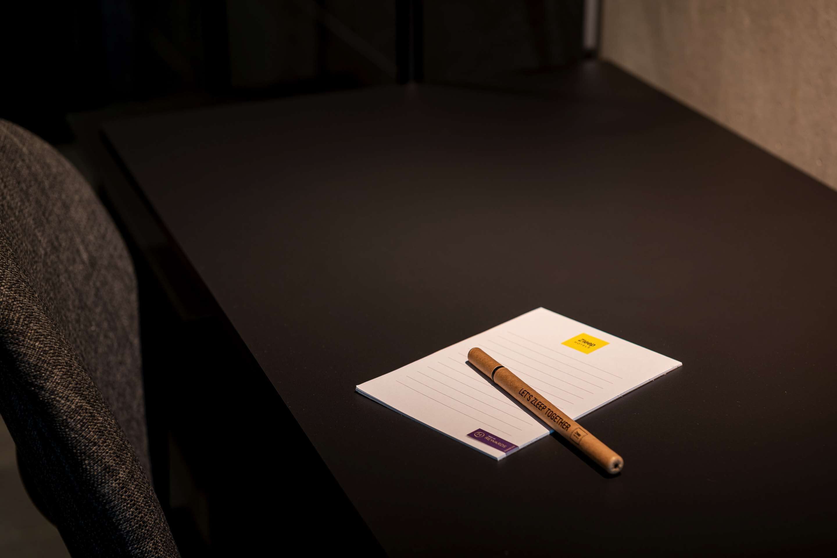 Une table en bois foncé, avec un bloc-notes et un stylo.