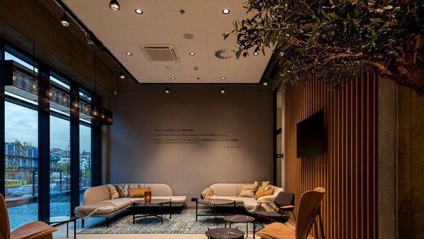 Een moderne hotellobby met twee banken, een salontafel en een aan de muur bevestigde televisie.