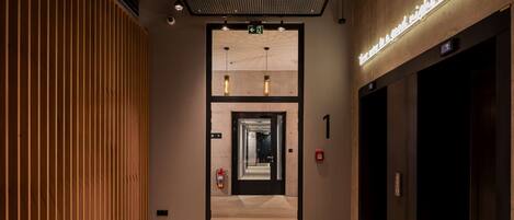 Un moderno vestíbulo de hotel con un panel de madera, un letrero de neón y un ascensor.