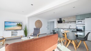 Una sala de estar moderna con televisor, sofá y comedor.